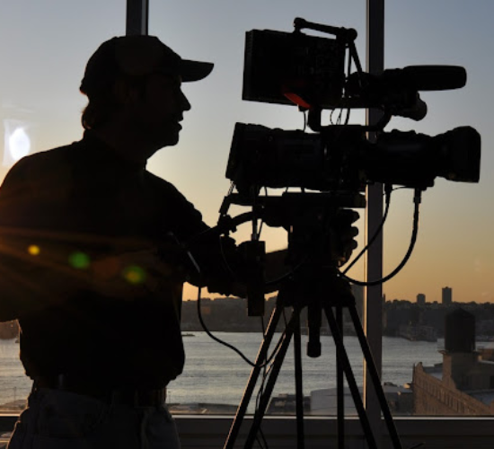 A cameraman captures the sunrise with his camera, offering the best video production services