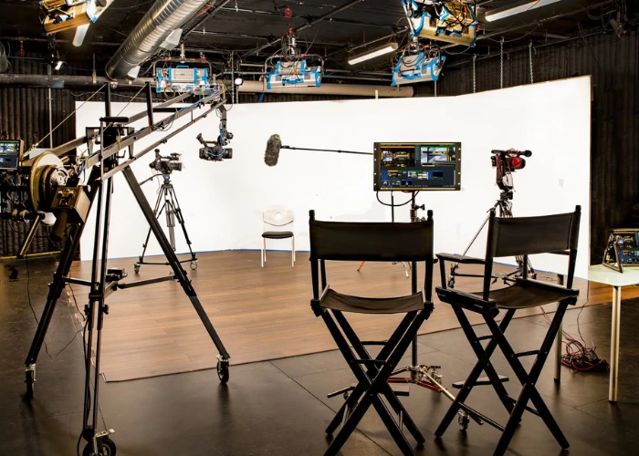 A professional video production studio equipped with lighting, cameras, monitors, and a setup for filming.