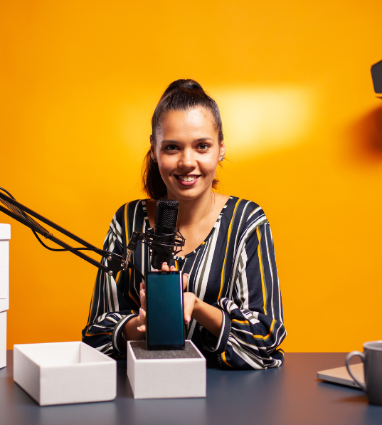 This confident woman is holding a microphone and amplifying her voice against a bright orange background