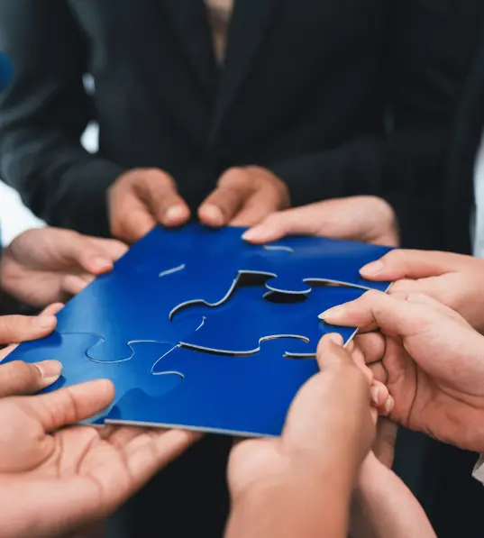 A group of professionals collaborating, holding blue puzzle pieces, symbolizing teamwork and unity.